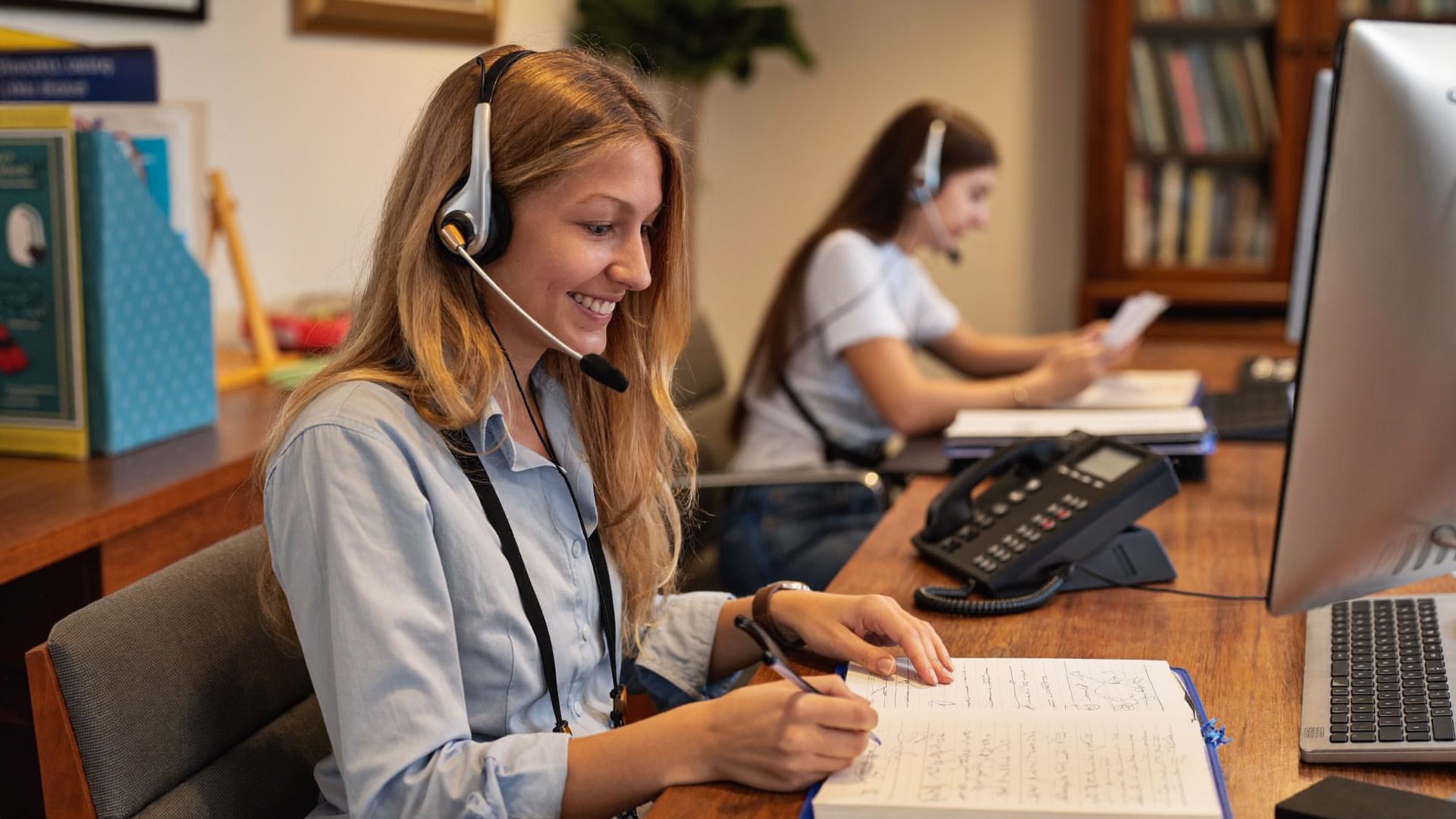 Advisor on a headset taking notes during a client call at the Kelmeg office